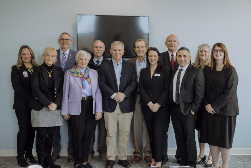 Attendees smile and pose for a group photo at a mental health roundtable event at RHA's Alamance Behavioral Health Center